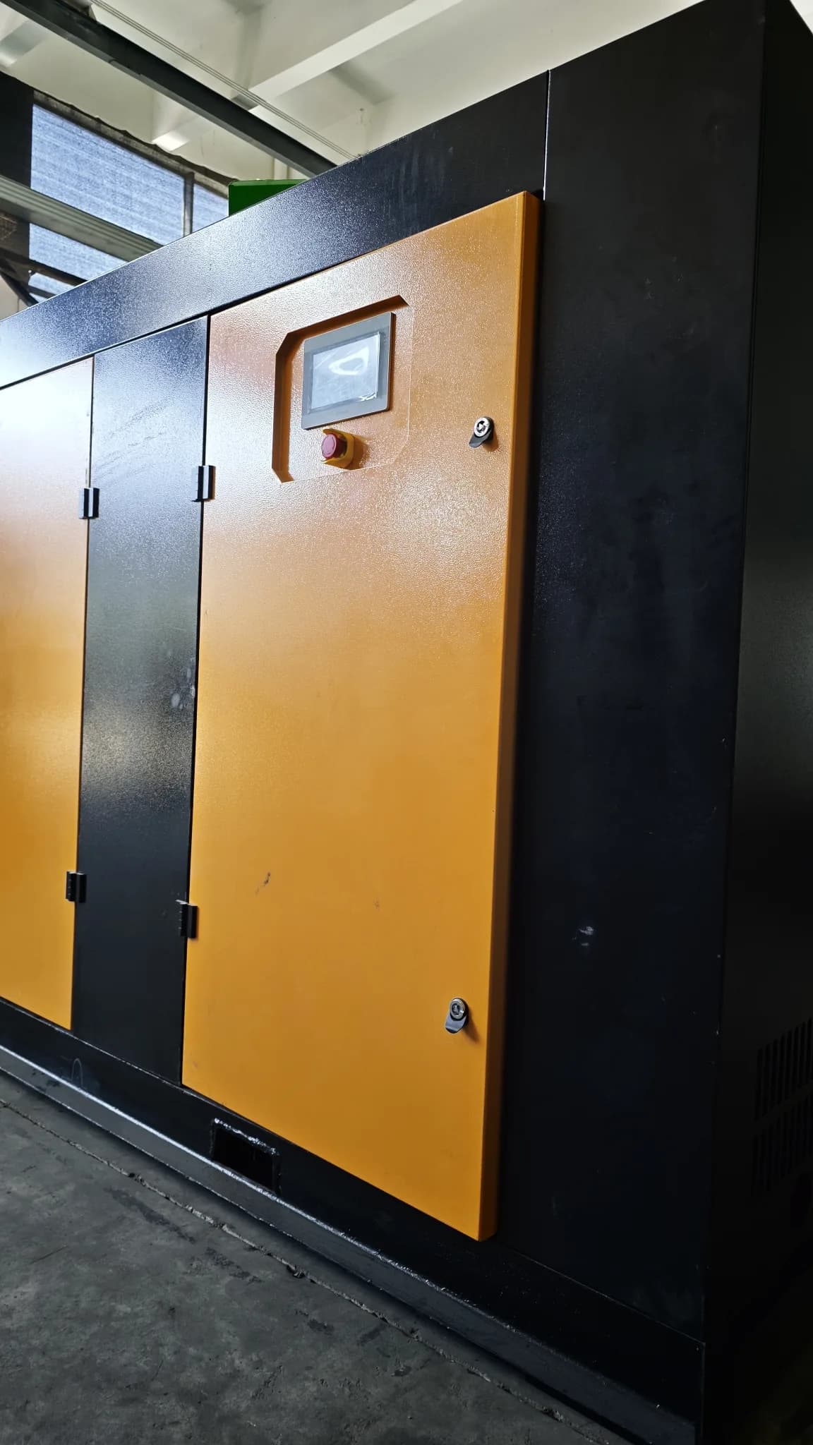 Black-and-orange oil-injected screw vacuum pump enclosure photographed in the SC workshop